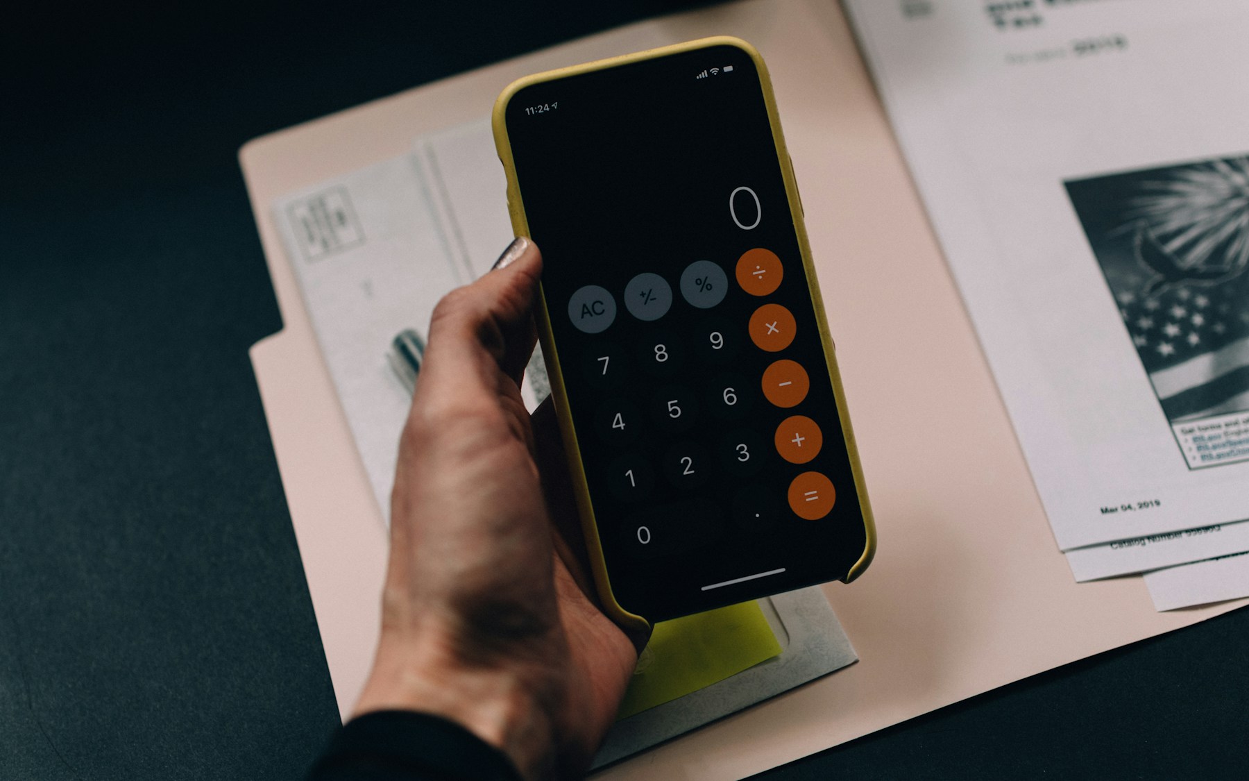Person reviewing calculations and financial documents with a phone calculator