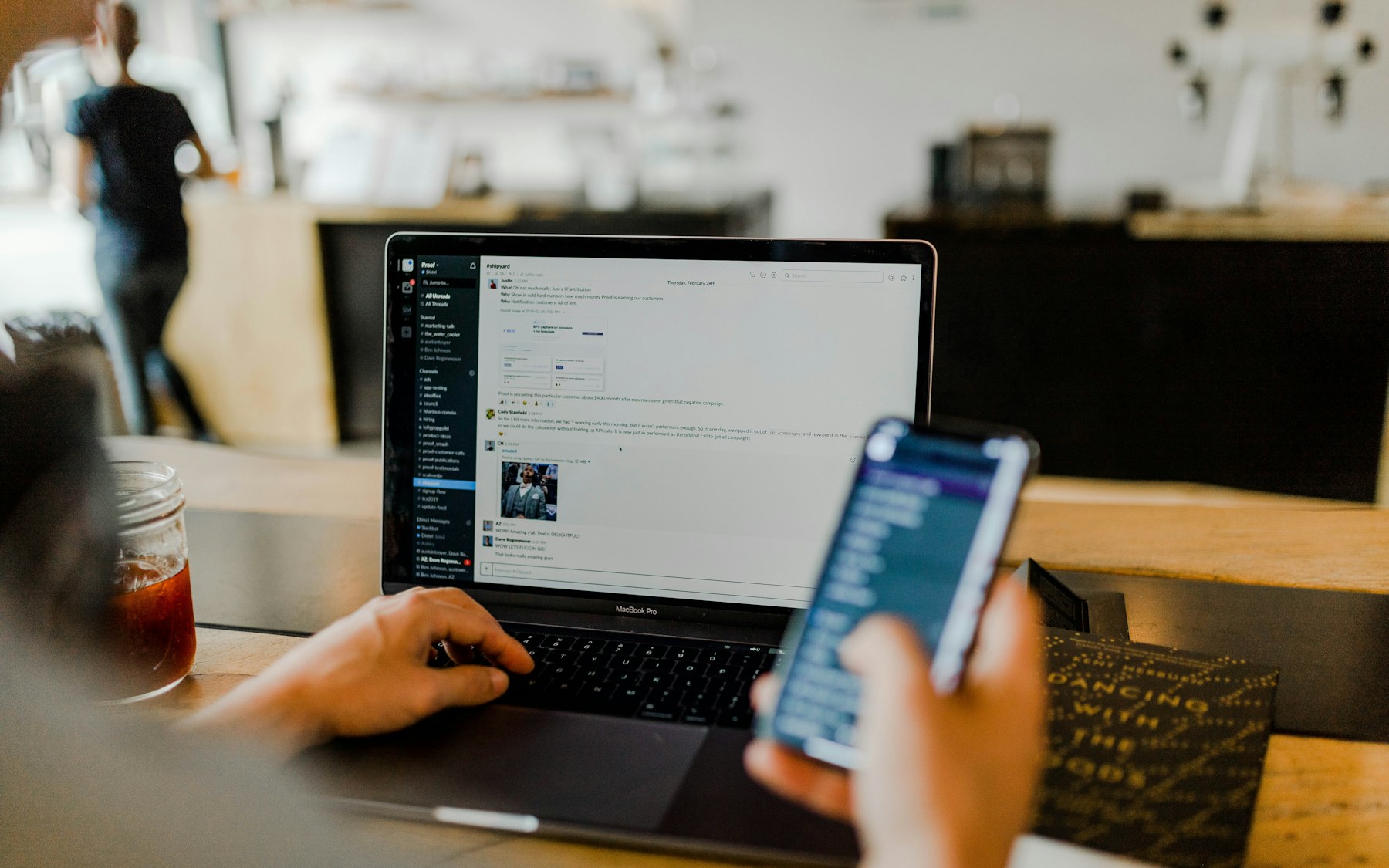 Person working across a laptop and smartphone at a desk