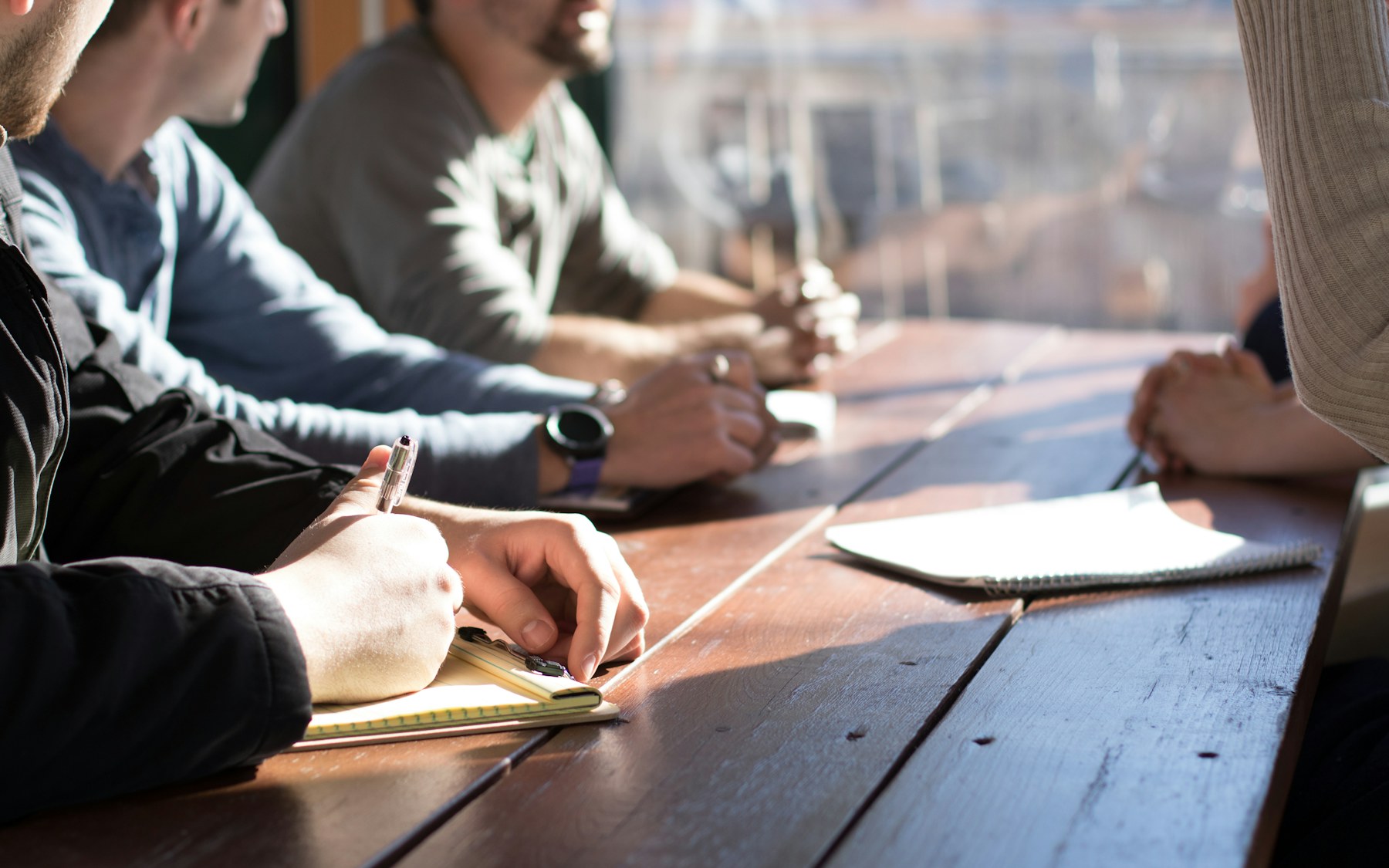 Colleagues taking notes around a wooden meeting table