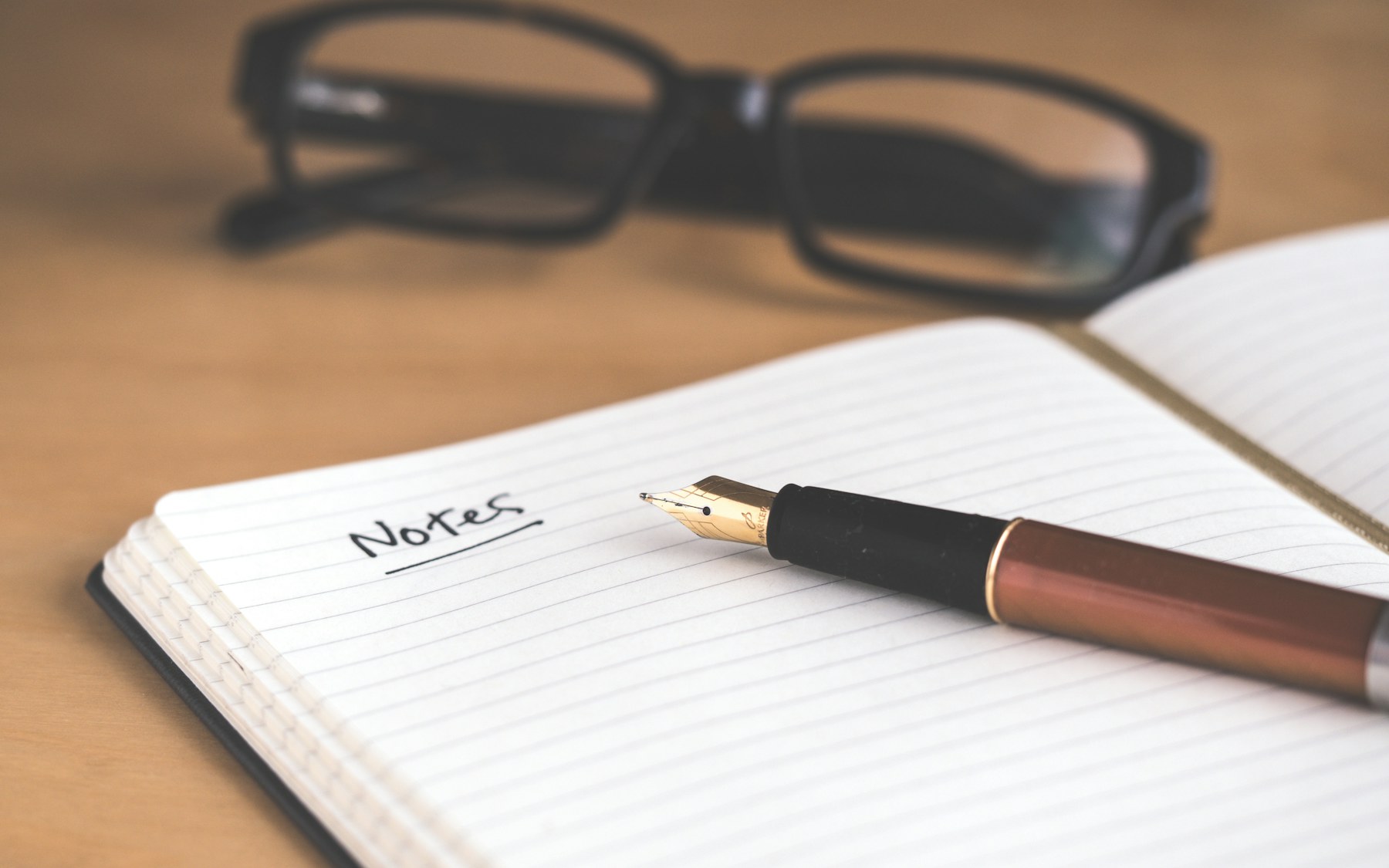 Open notebook labeled Notes with a fountain pen and reading glasses