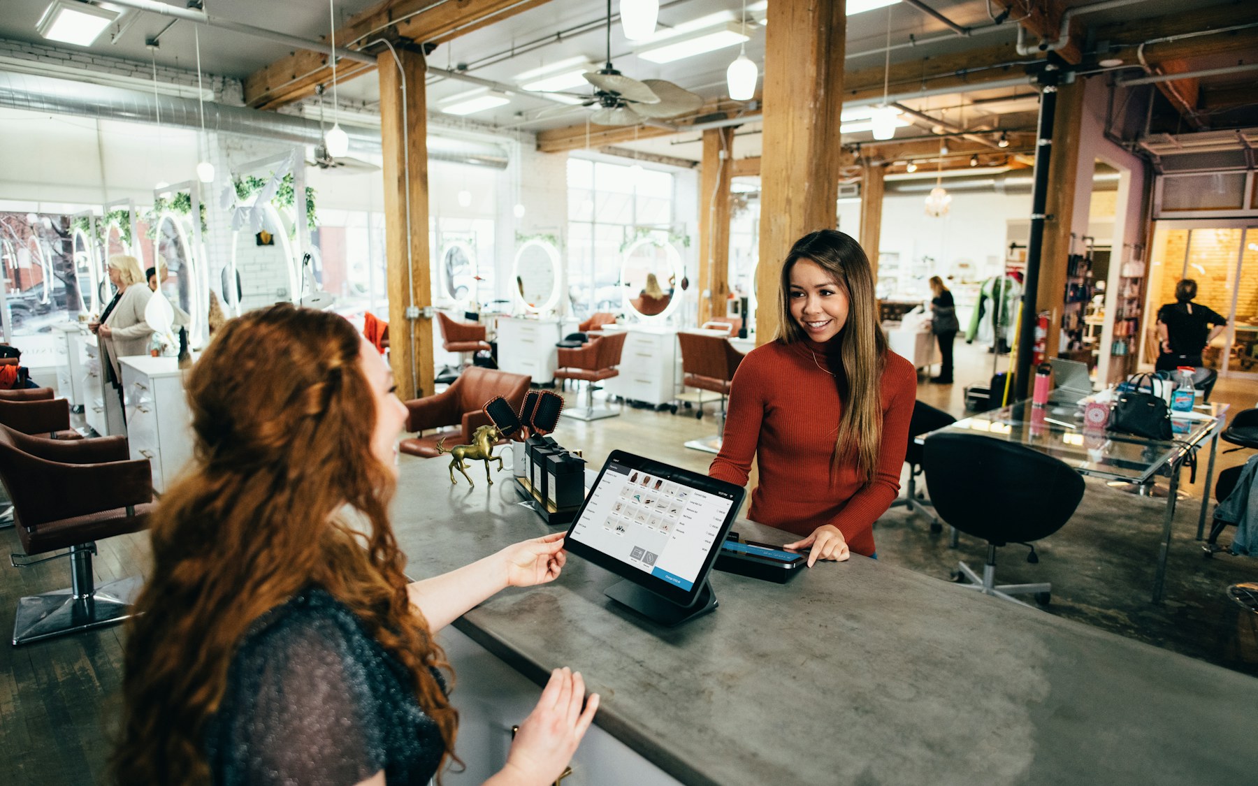 Small business owner checking in a customer at a front-desk tablet